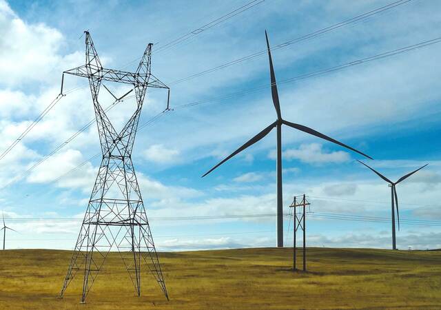 Wind turbines positioned on a plain next to electric grid towers