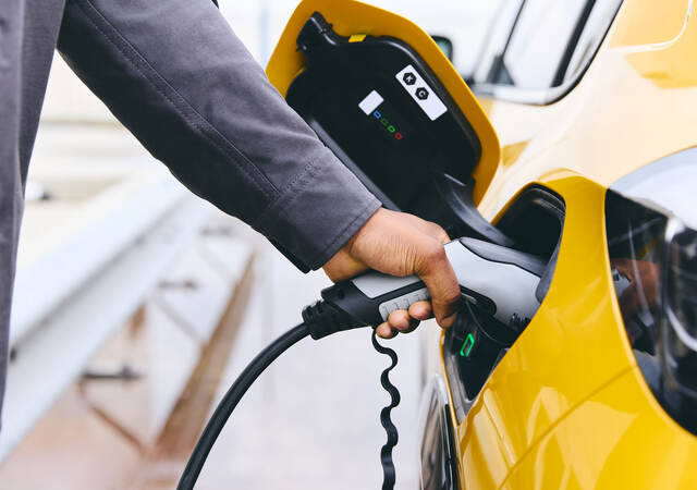 Person plugging their electric vehicle into a charger