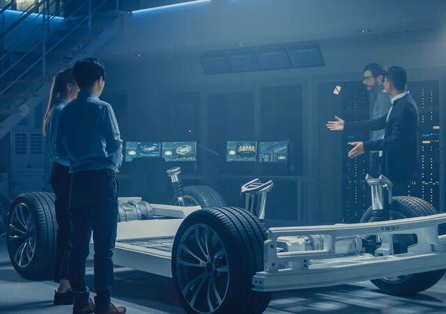 Four people working around a base of an electric car