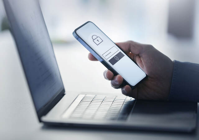 a person using a cellphone to unlock an app on a laptop