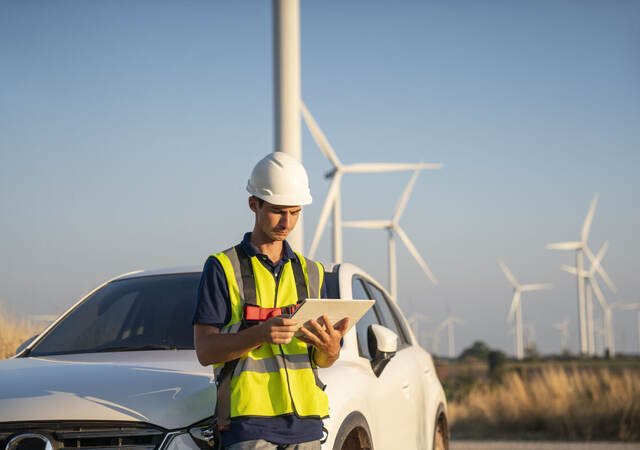 Construction worker in a wind farm reading data on a tablet