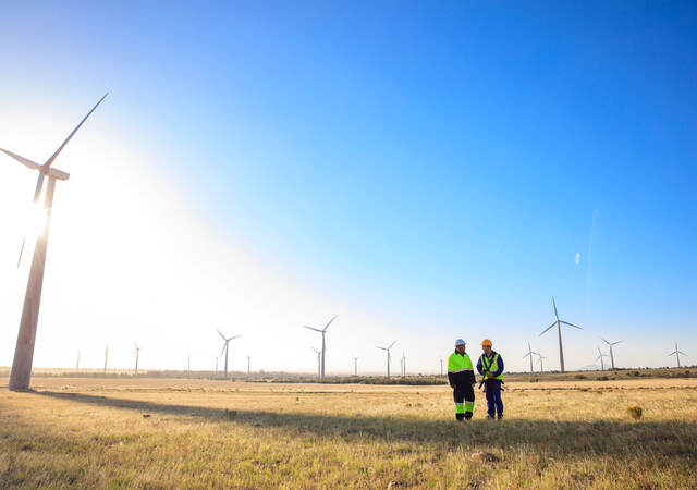 Engineers standing next to a wind turbine at a windfarm