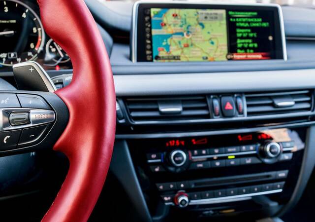 Modern car interior, red steering wheel with media phone control buttons,navigation, screen multimedia system background, car interior details