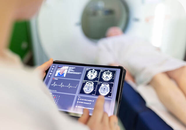 Neurologist examining patient's CAT scan images on digital table in a clinic