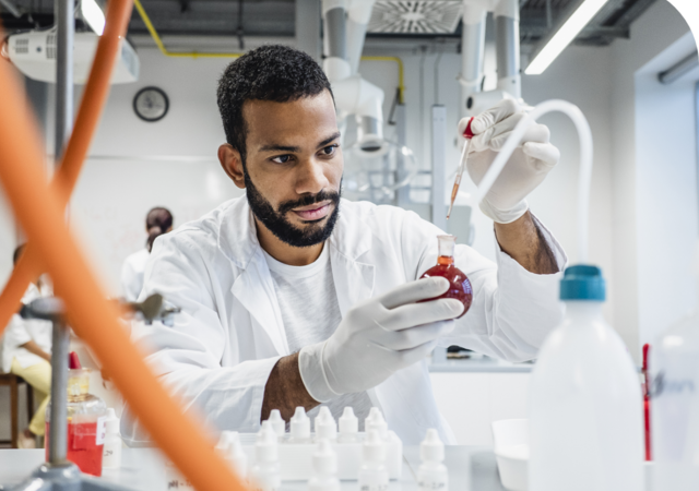 scientist dropping a chemical into round bottom flask