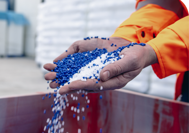 person in warehouse picking up handfuls of blue and white chemical pellets