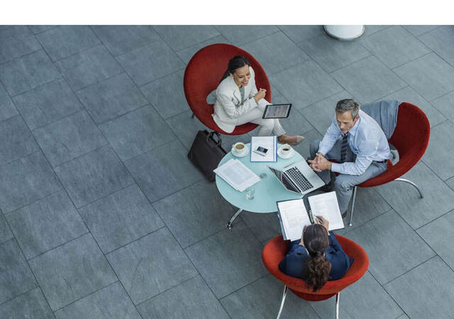 Three people in a workplace lobby having an informal discussion