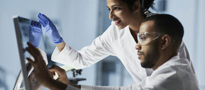 Scientists in laboratory working with computer and microscope