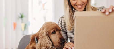 Woman sitting next to her dog while opening a package