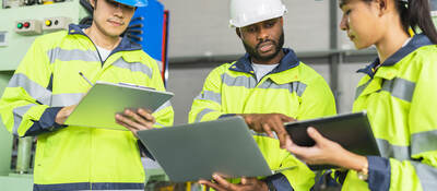 Workers in PPE holding clipboards and talking