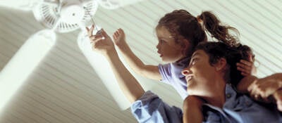 Mother and daughter turning on a ceiling fan.