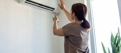 Woman turning on air conditioner.