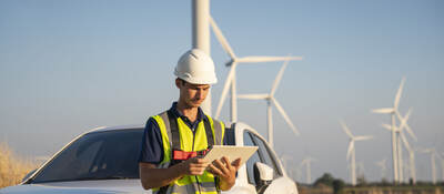 Construction worker in a wind farm reading data on a tablet