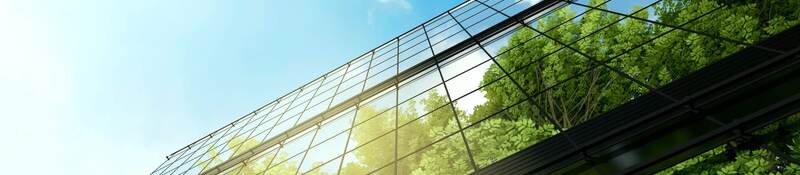 Upward view of a reflection of trees against glass skyscrapers