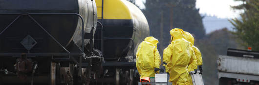 HAZMAT team members investigate chemical disaster near railroad tracks