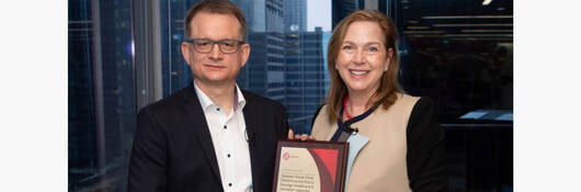 Dirk Vielsäcker receives a plaque from Jennifer Scanlong commemorating the first certification using modeling and simulation technolog