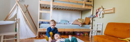 Two little boys playing in their room in front of their bunk bed.