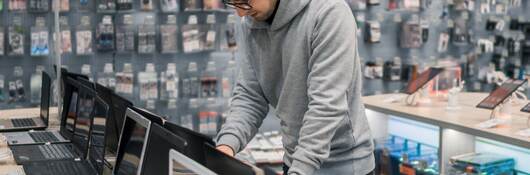 Modern male customer choosing laptop in the computer shop.