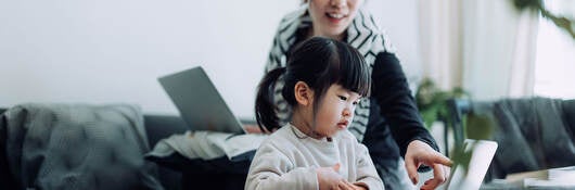 Mother with laptop and child looking at a personal device