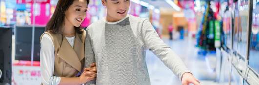 Young couple buying television in electronics store