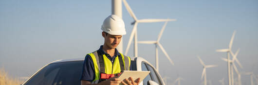 Construction worker in a wind farm reading data on a tablet