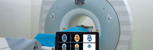 CT scanner and a person holding a tablet with scans on the screen