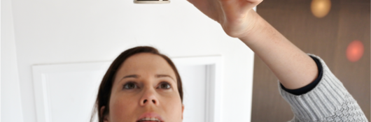 smoke alarm with woman checking the alarm's status