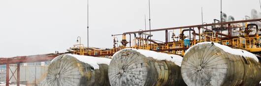 Large horizontal shell-and-tube tanks heat exchangers with liquid at an industrial petroleum refining petrochemical chemical plant in the snow in winter