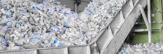 Closeup escalator with a pile of plastic bottles at the factory for processing and recycling. PET recycling plant