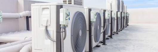 Heat pumps on a roof with a blue sky and light clouds in the background