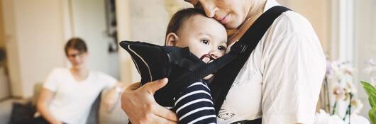 Mother holding baby in soft carrier