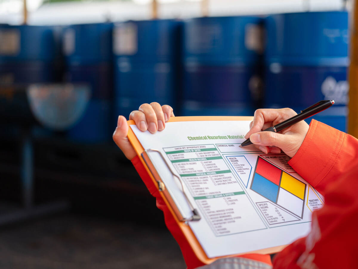 Worker checking chemical hazardous communication form on a clipboard.