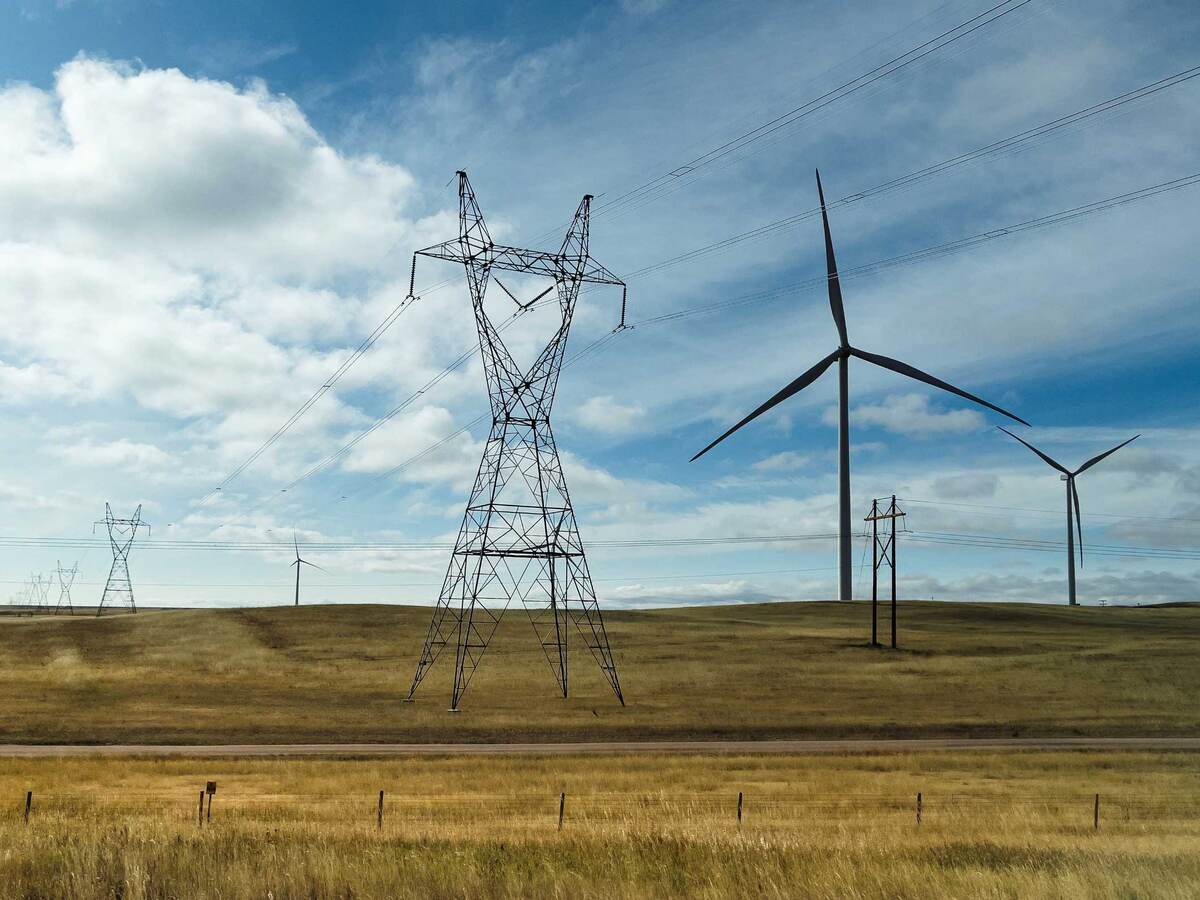 Wind turbines positioned on a plain next to electric grid towers