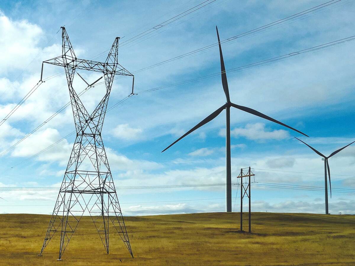 Wind turbines positioned on a plain next to electric grid towers