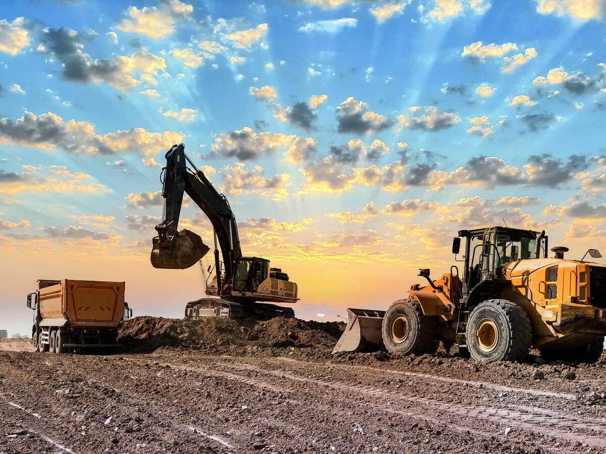 Excavator and bulldozer working together to put dirt into a dump truck