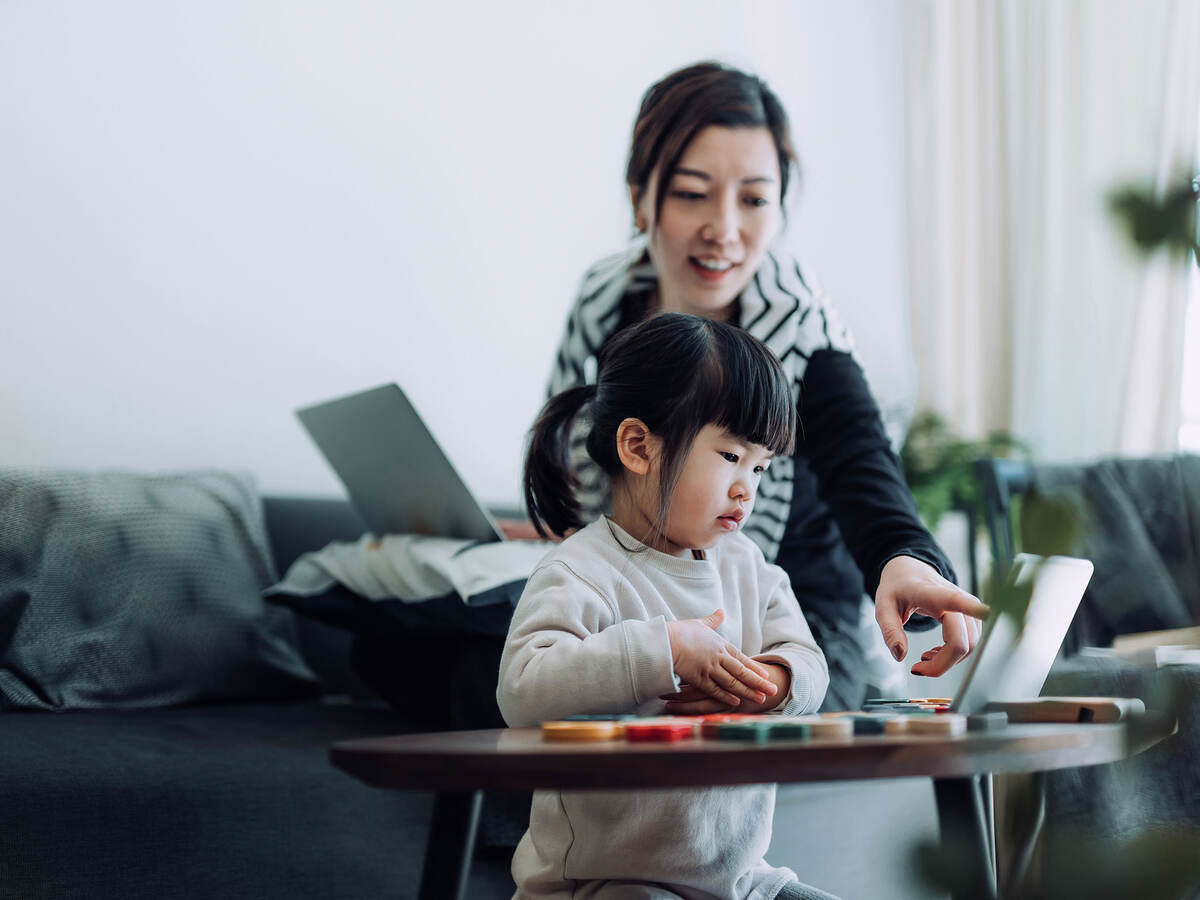 Mother with laptop and child looking at a personal device