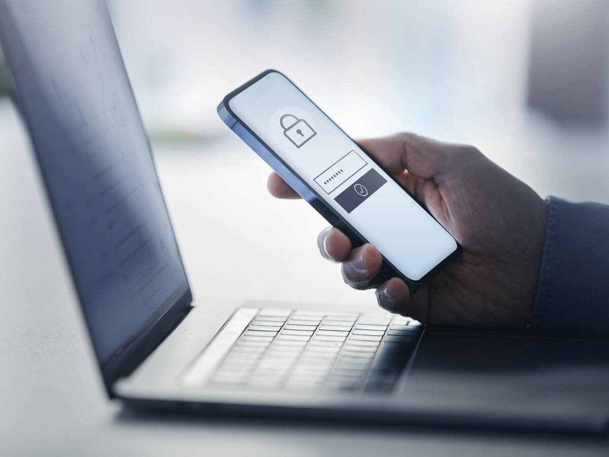 a person using a cellphone to unlock an app on a laptop