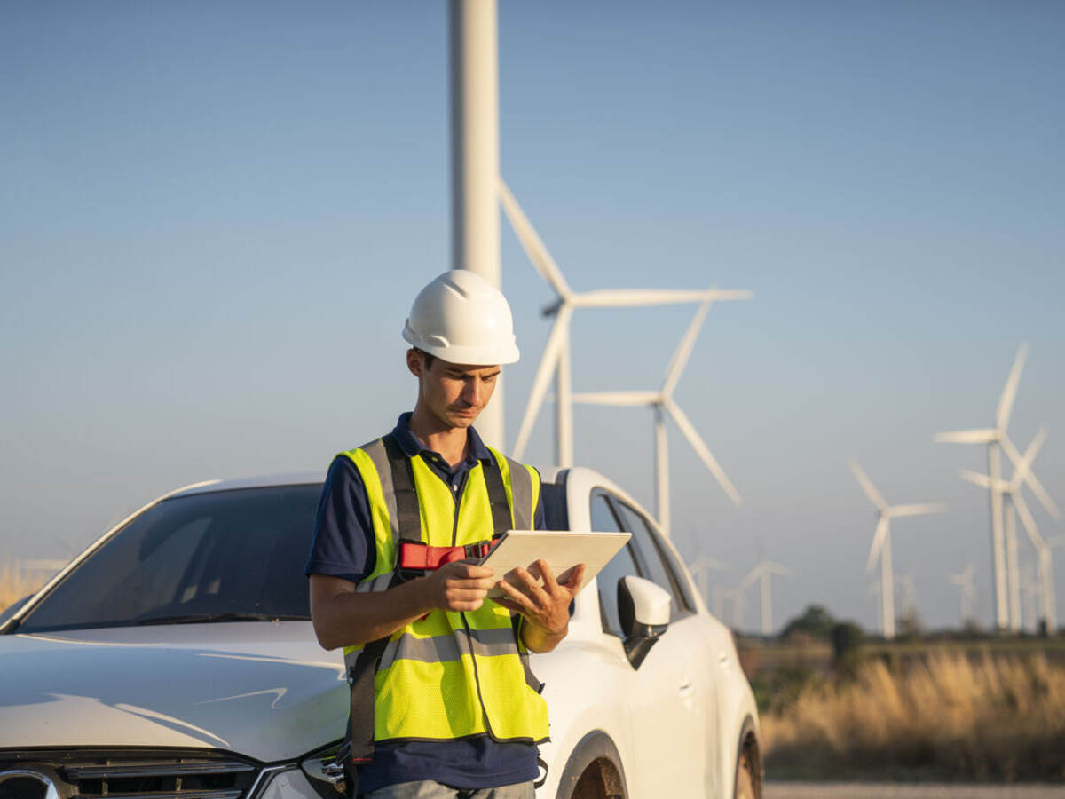 Construction worker in a wind farm reading data on a tablet