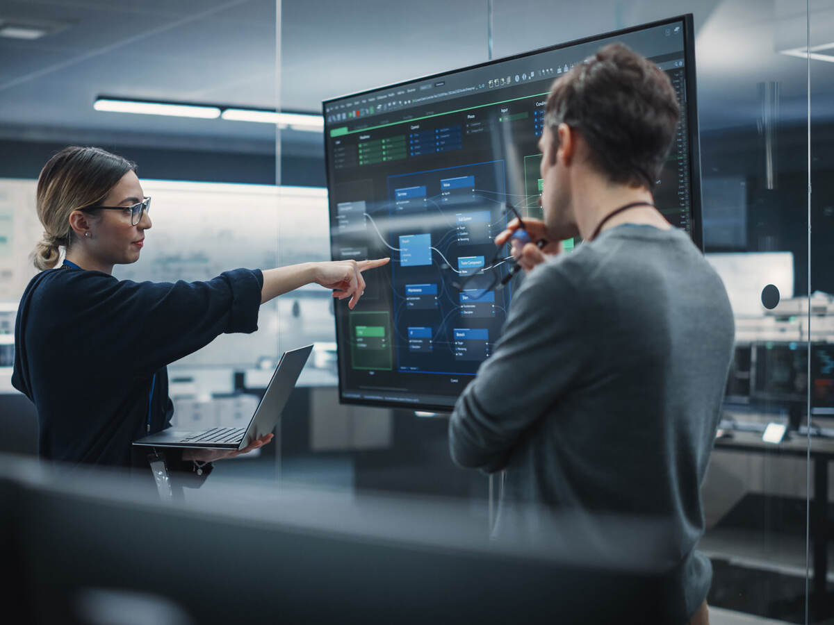 a person pointing at a screen, with another person watching