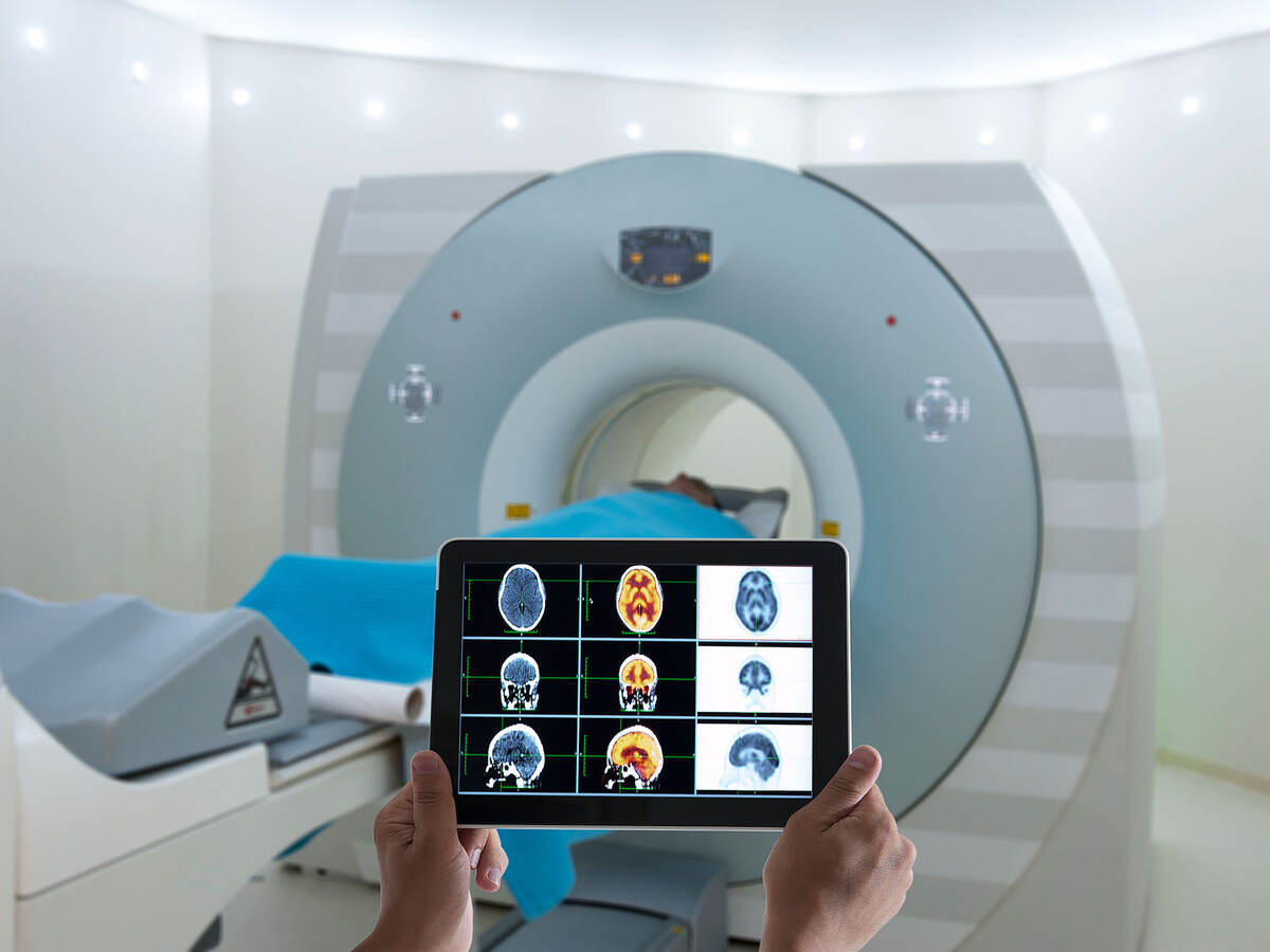 CT scanner and a person holding a tablet with scans on the screen