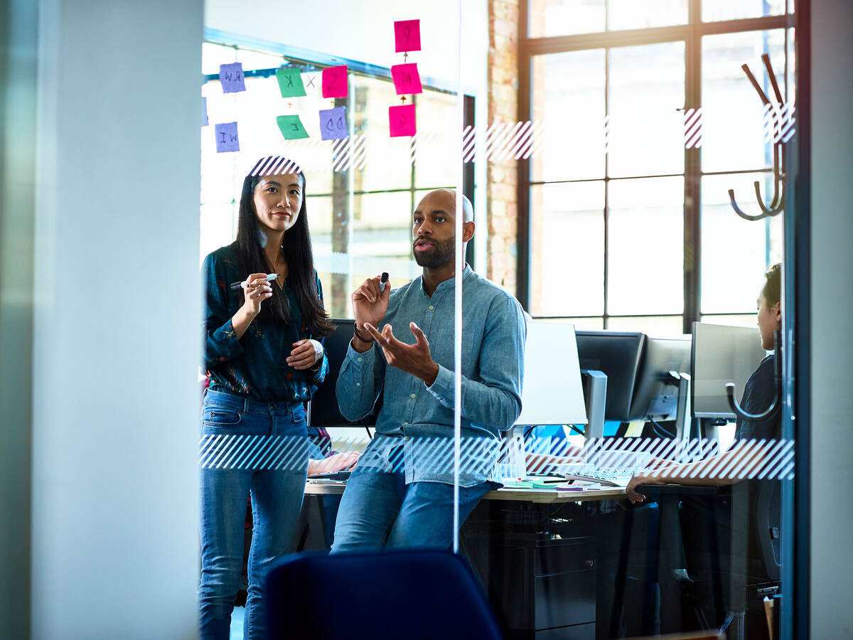 Two business people discussing in modern office with sticky notes