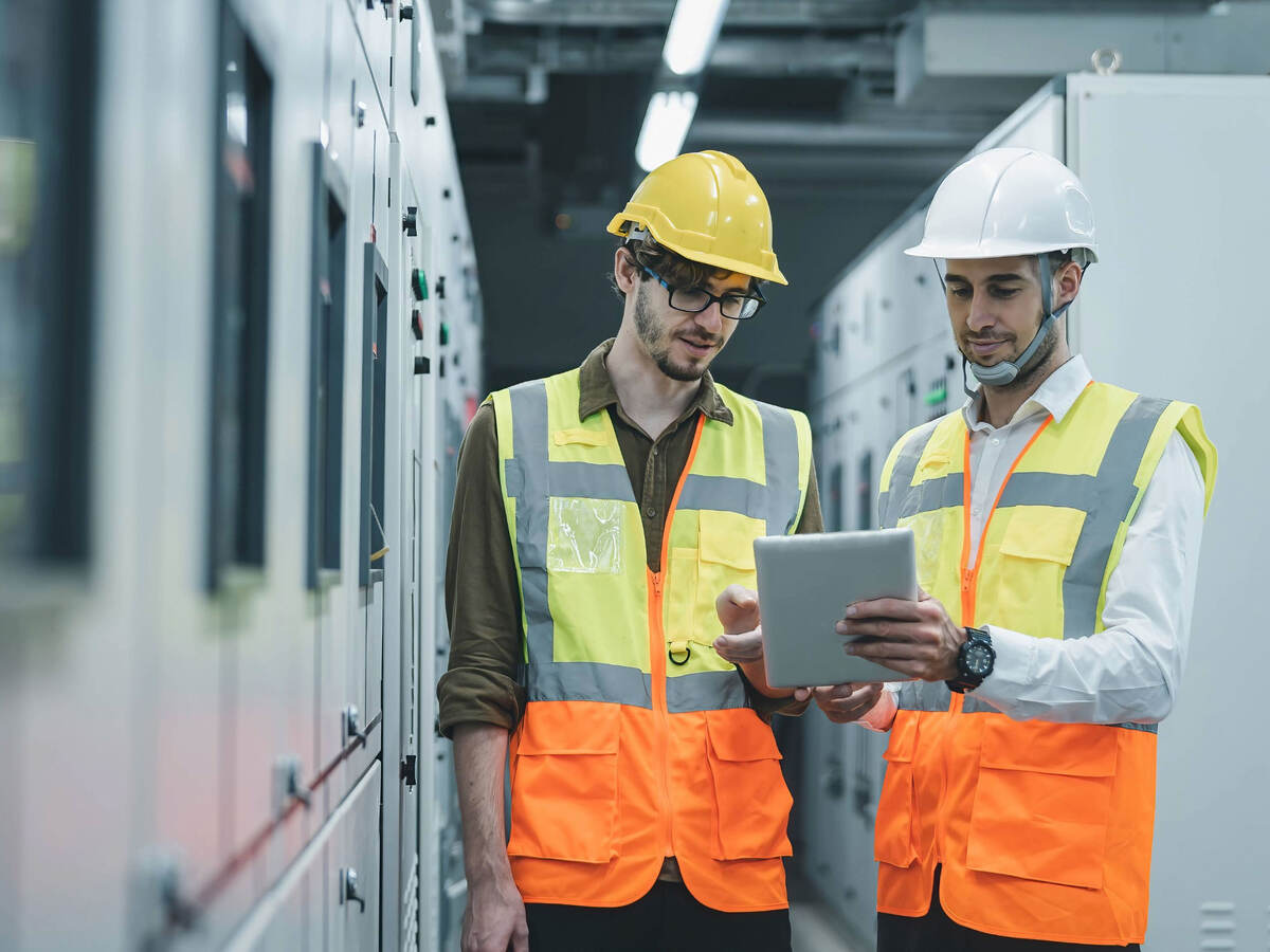 Two engineers working and checking status on a switchgear electrical energy distribution at a substation room