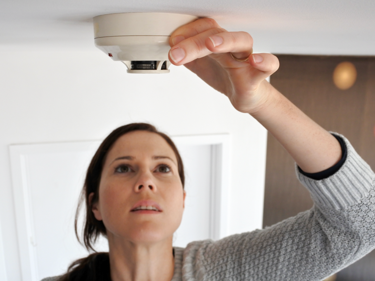 smoke alarm with woman checking the alarm's status