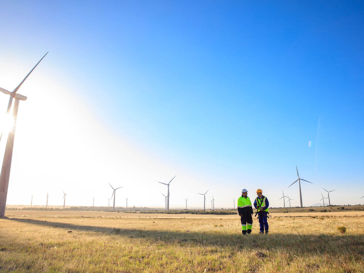 Engineers standing next to a wind turbine at a windfarm