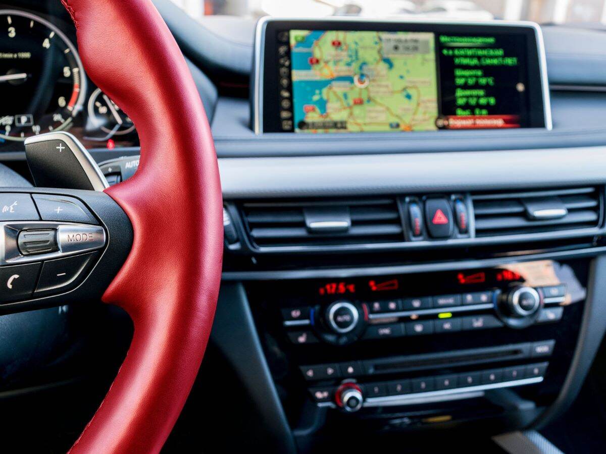 Modern car interior, red steering wheel with media phone control buttons,navigation, screen multimedia system background, car interior details