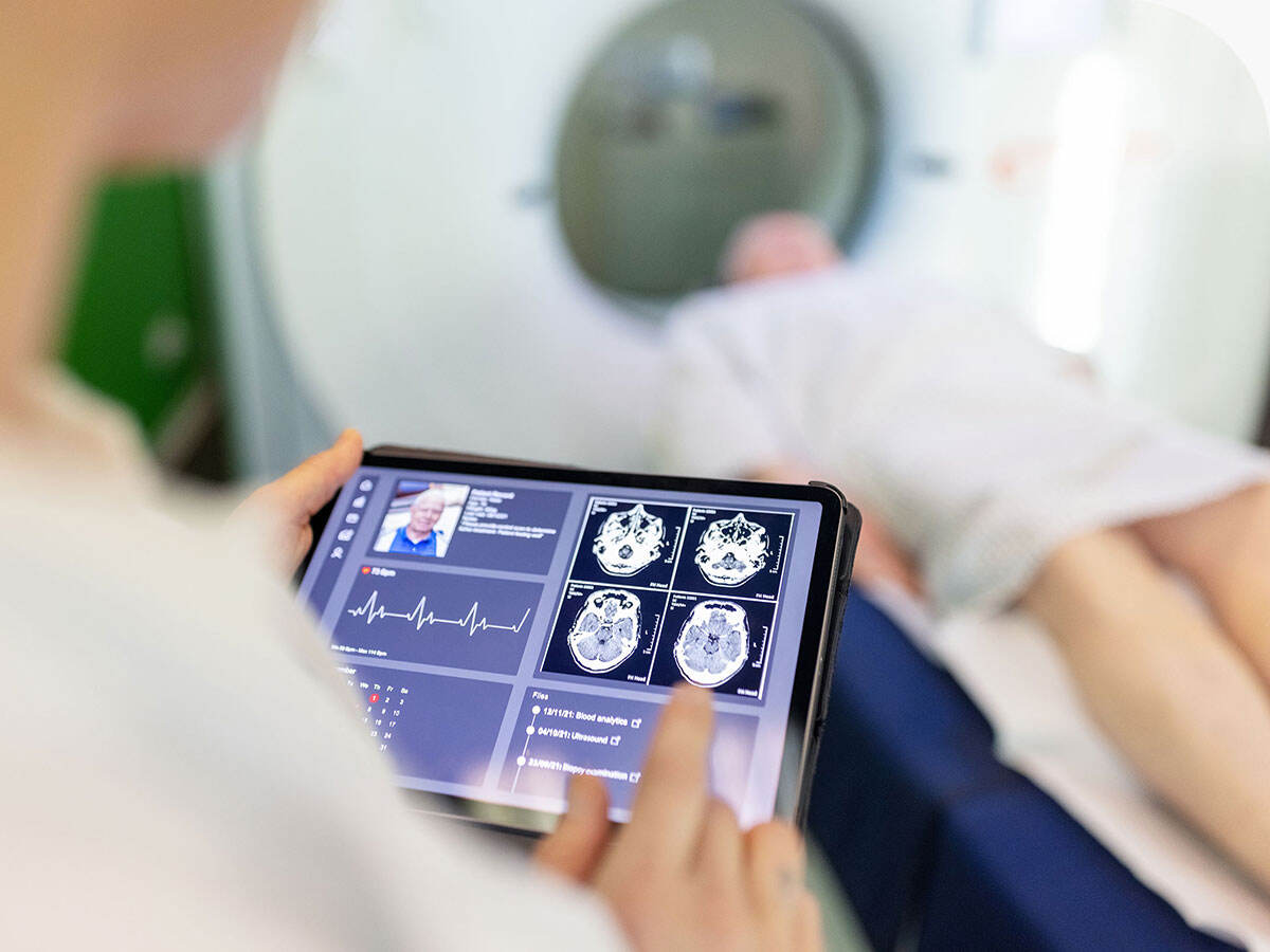 Neurologist examining patient's CAT scan images on digital table in a clinic