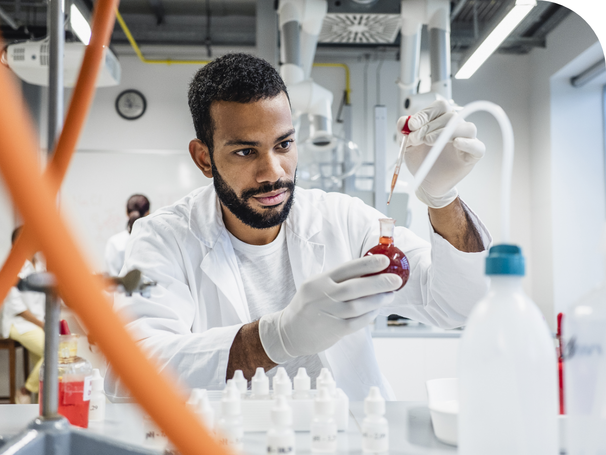 scientist dropping a chemical into round bottom flask