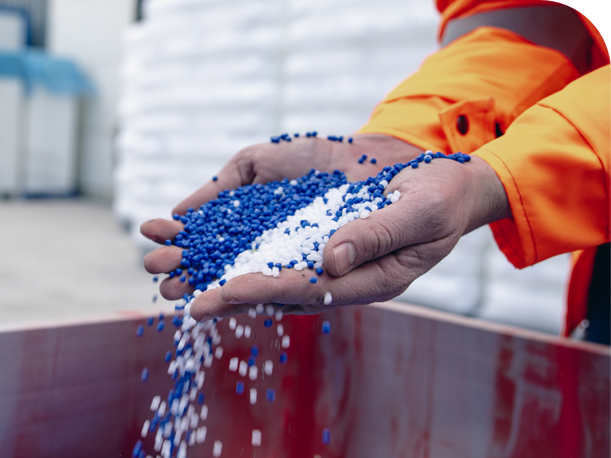 person in warehouse picking up handfuls of blue and white chemical pellets