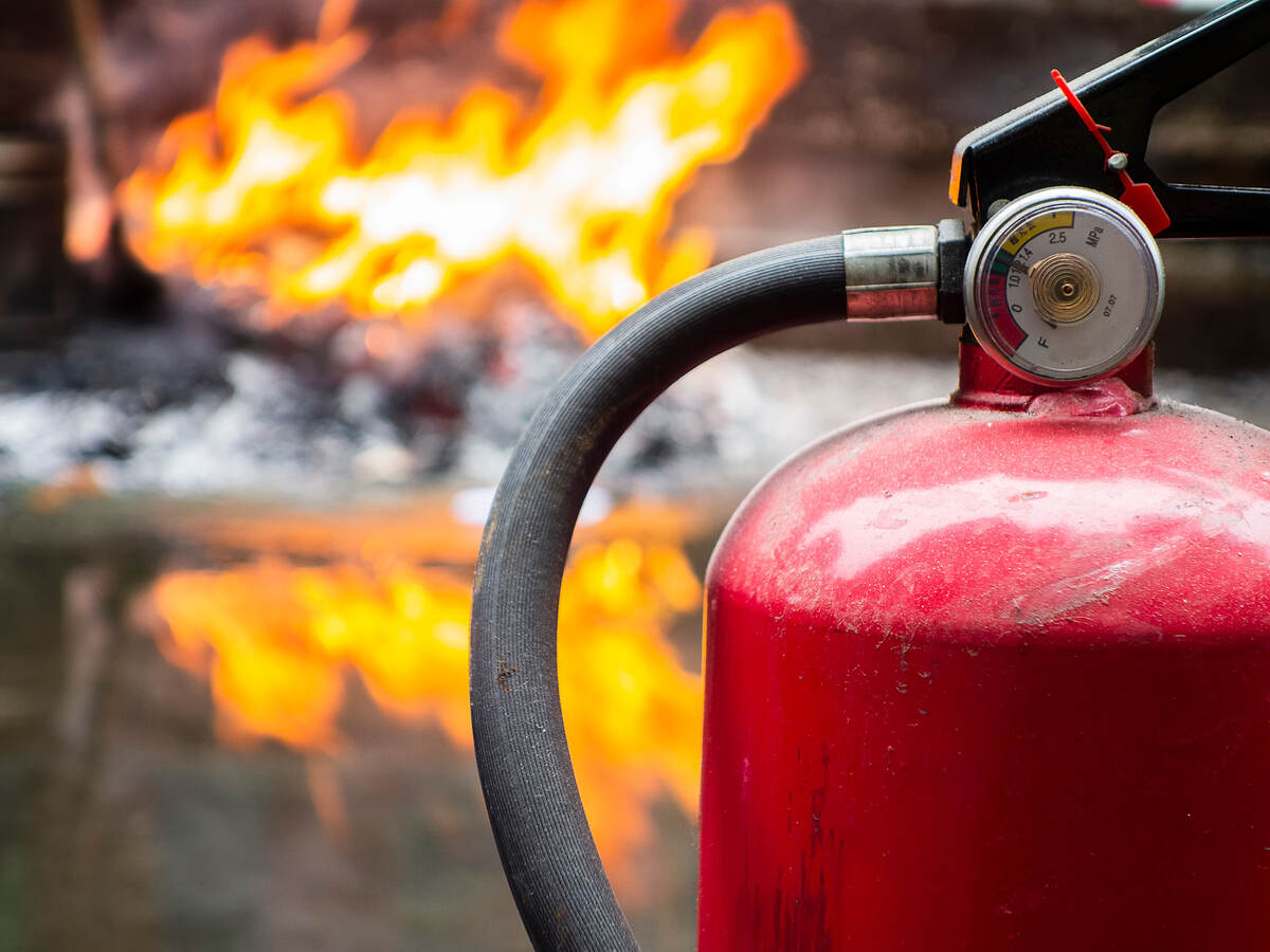 Fire extinguisher in foreground with flames in background