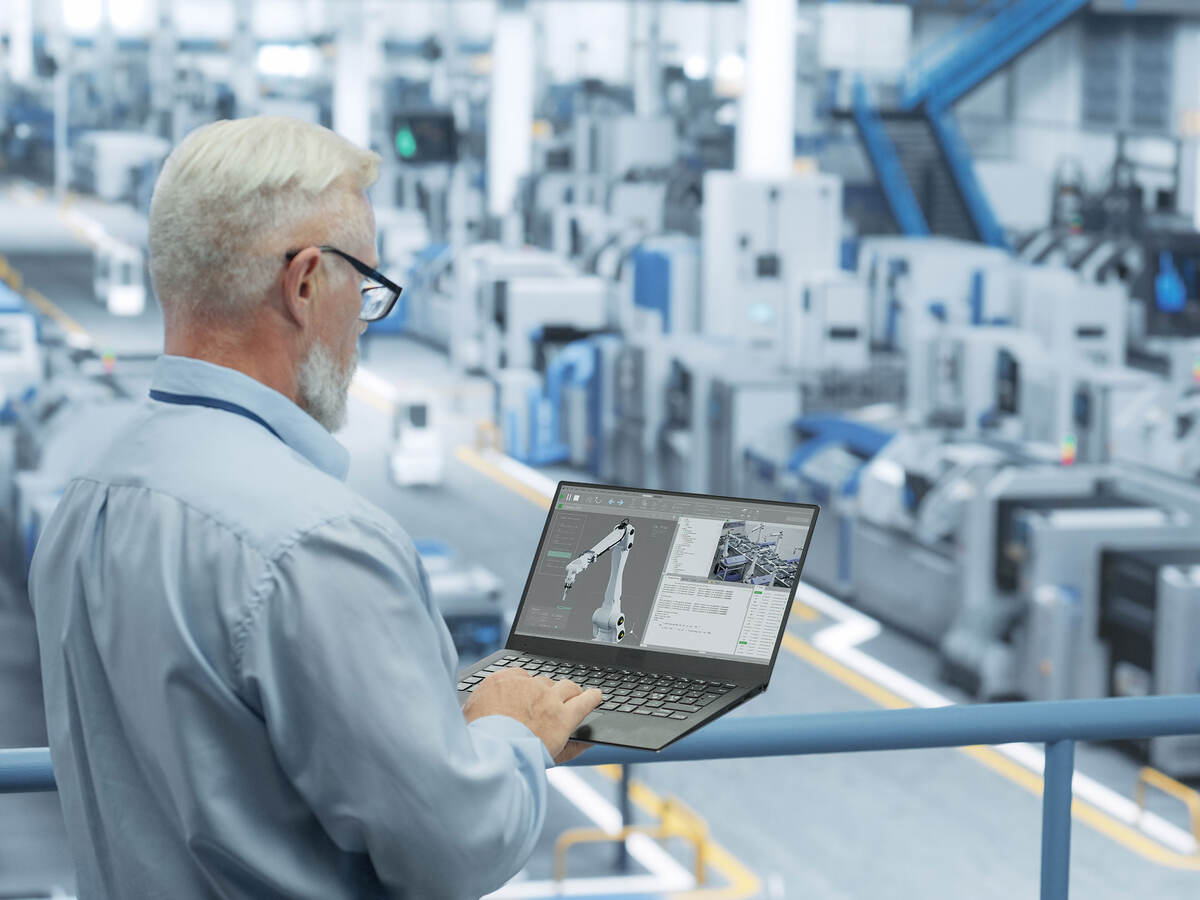 A person working on a factory floor with a laptop